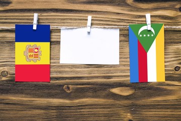 Hanging flags of Andorra and Comoros attached to rope with clothes pins with copy space on white...