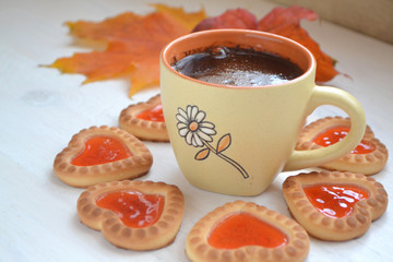 Cookies in form of little heart and autumn maple leaf with coffee cup on old wooden background