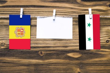 Hanging flags of Andorra and Syria attached to rope with clothes pins with copy space on white note...