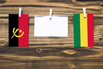 Hanging flags of Angola and Bolivia attached to rope with clothes pins with copy space on white...