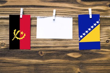 Hanging flags of Angola and Bosnia Herzegovina attached to rope with clothes pins with copy space...