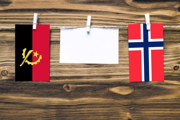 Hanging flags of Angola and Bouvet Islands attached to rope with clothes pins with copy space on...