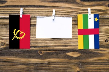 Hanging flags of Angola and Central African Republic attached to rope with clothes pins with copy...