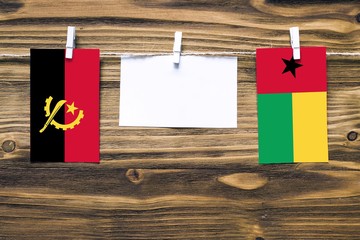 Hanging flags of Angola and Guinea Bissau attached to rope with clothes pins with copy space on...