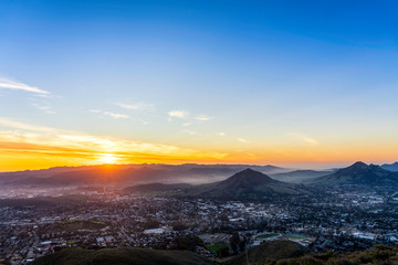 Fototapeta premium Setting Sun over Hills, Mountain Peaks, City