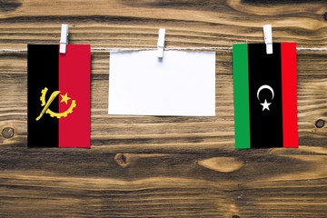 Hanging flags of Angola and Libya attached to rope with clothes pins with copy space on white note...