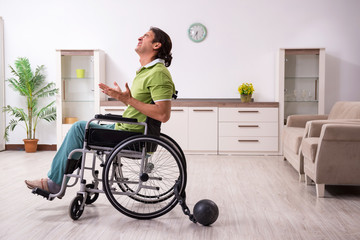 Young male invalid in wheel-chair suffering at home