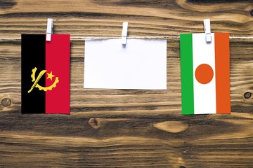 Hanging flags of Angola and Niger attached to rope with clothes pins with copy space on white note...