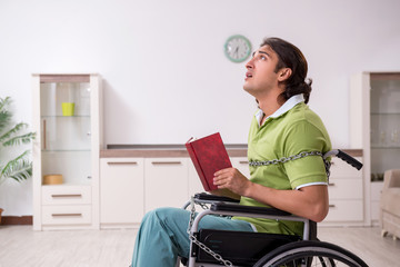 Young male invalid in wheel-chair suffering at home