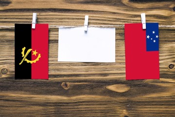 Hanging flags of Angola and Samoa attached to rope with clothes pins with copy space on white note...