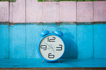 Blue vintage alarm clocks on blue wooden table and light blue and pink background wall