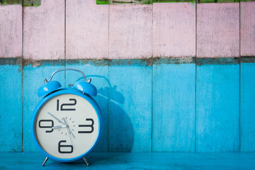 Blue vintage alarm clocks on blue wooden table and light blue and pink background wall