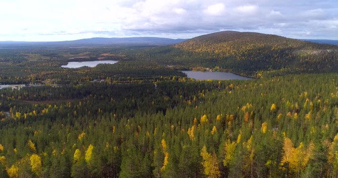 Autumn in Lapland, Aerial, reverse, drone shot, over autumn color, foliage forest, of Katkatunturi, lake Immeljarvi and arctic wilderness, on a partly sunny, fall day, on Levitunturi, in Levi, Finland