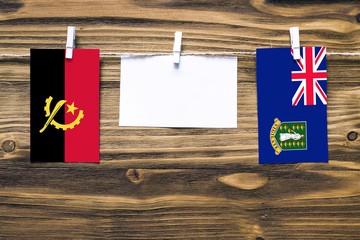Hanging flags of Angola and British Virgin Islands attached to rope with clothes pins with copy...