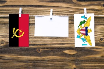 Hanging flags of Angola and United States Virgin Islands attached to rope with clothes pins with...