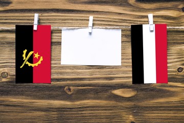Hanging flags of Angola and Yemen attached to rope with clothes pins with copy space on white note...
