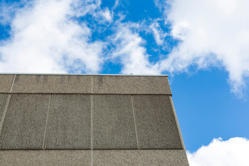 The edge of a concrete building with clouds and blue sky