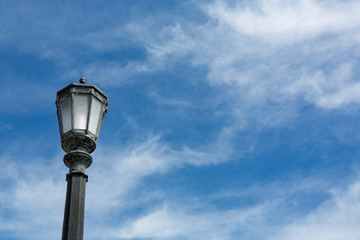 Fototapeta na wymiar Single street lamp against a blue sky with clouds