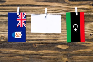 Hanging flags of Anguilla and Libya attached to rope with clothes pins with copy space on white...
