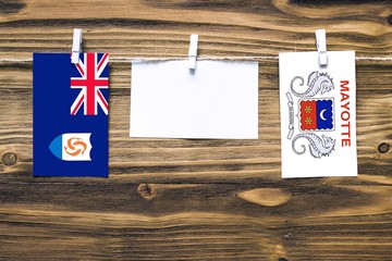 Hanging flags of Anguilla and Mayotte attached to rope with clothes pins with copy space on white...