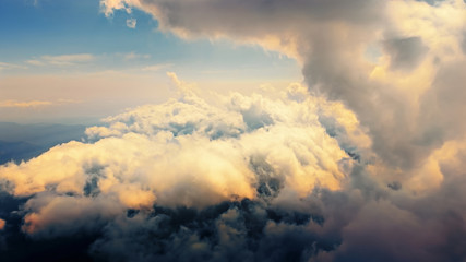 Flying through heavenly beautiful cloudscape. of warm tone fluffy clouds moving softly on the pale blue sky in the evening sunshine. View from the cockpit.