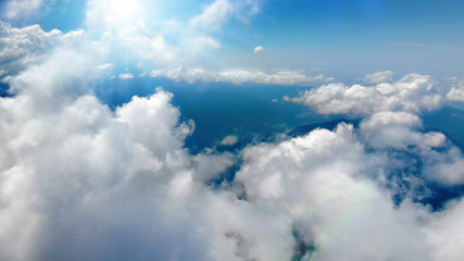 Flying through heavenly beautiful sunny cloudscape. Picturesque of white fluffy clouds moving softly on the clear blue sky in pure sunshine. Direct view from the cockpit.