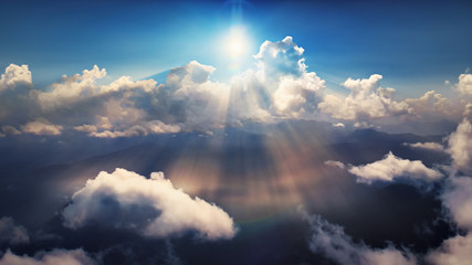 Flying through heavenly beautiful sunny cloudscape. Amazing of golden fluffy clouds moving softly on the sky and the sun shining above the clouds with beautiful rays and lens flare.