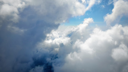 Flying through beautiful thick fluffy clouds. Amazing of soft white clouds moving slowly on the clear blue sky in pure daylight. Direct view from the cockpit.