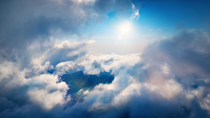 Flying through heavenly beautiful sunny cloudscape. Amazing of white fluffy clouds moving softly on the sky and the sun shining above the clouds with beautiful rays and lens flare.