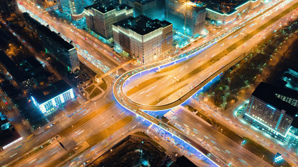 Fototapeta na wymiar Beautiful motion of the big road junction on the night, view from above. Aerial shot of busy crossroad in Moscow center with a lot of traffic and glittering city lights.