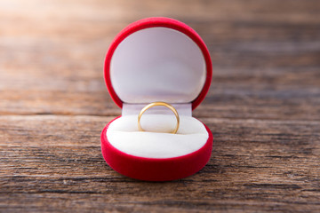 Gold ring in red ring box on wooden background  with sunlight