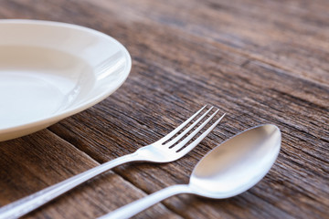 Selective focus of White dish and fork and spoon cutlery  on a wooden background