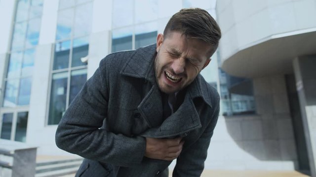 Young man suddenly feeling acute pain in chest, risk of stroke, heart attack