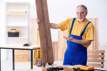 Old male carpenter working in workshop