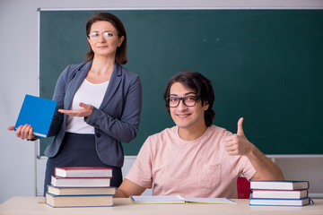 Old female teacher and male student in the classroom