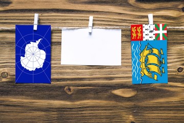 Hanging flags of Antarctica and Saint Pierre And Miquelon attached to rope with clothes pins with...