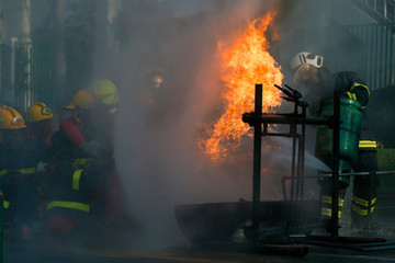   Photos Firefighter in fire fighting suit spraying water, Firemen fighting raging fire with huge...