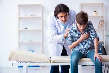 Male doctor examining boy by stethoscope