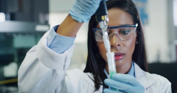 Portrait of dark skin female scientist is analyzing with a pipette a liquid to extract the DNA and molecules in the test tubes in laboratory. 