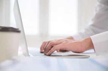 Close up image of businessman hands working computer laptop searching or typing text message for new project on desk in office room