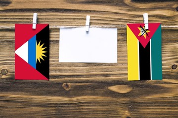 Hanging flags of Antigua and Barbuda and Mozambique attached to rope with clothes pins with copy...