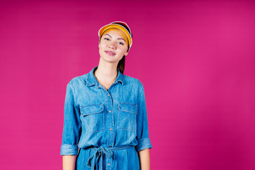 a woman stands static and smiles in a visor and denim shirt. background pink