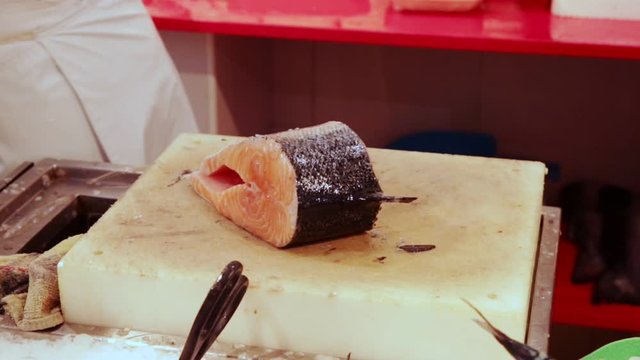 Hands of fishmonger cutting fresh raw salmon in shoper cutting salmon