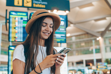 at the airport, a tourist reads a nice sms on the phone, with a smile