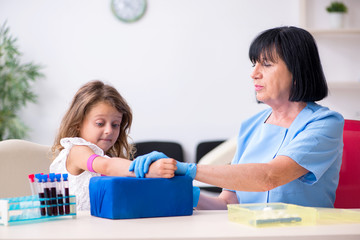 Little girl visiting old female doctor