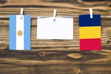 Hanging flags of Argentina and Chad attached to rope with clothes pins with copy space on white...