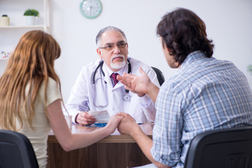 Obraz premium Young couple visiting old male doctor