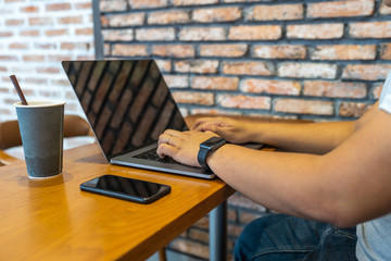 Freelancer typing laptop next to smartphone at coffee table