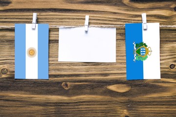 Hanging flags of Argentina and San Marino attached to rope with clothes pins with copy space on...