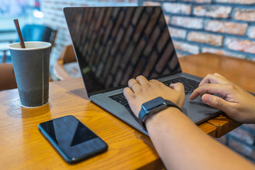 Closeup photo of human hand typing laptop keyboard at coffeeshop